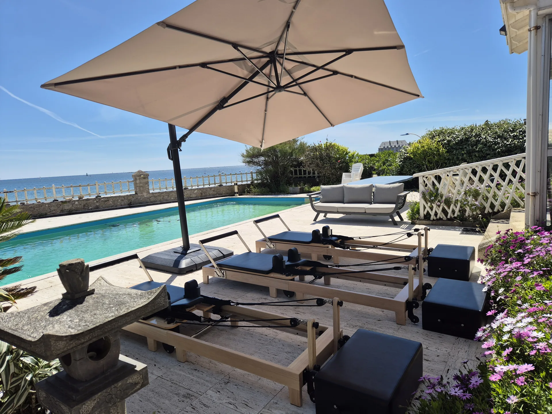 Cours de Pilates Reformer en plein air avec parasol et vue sur la mer à Larmor-Plage