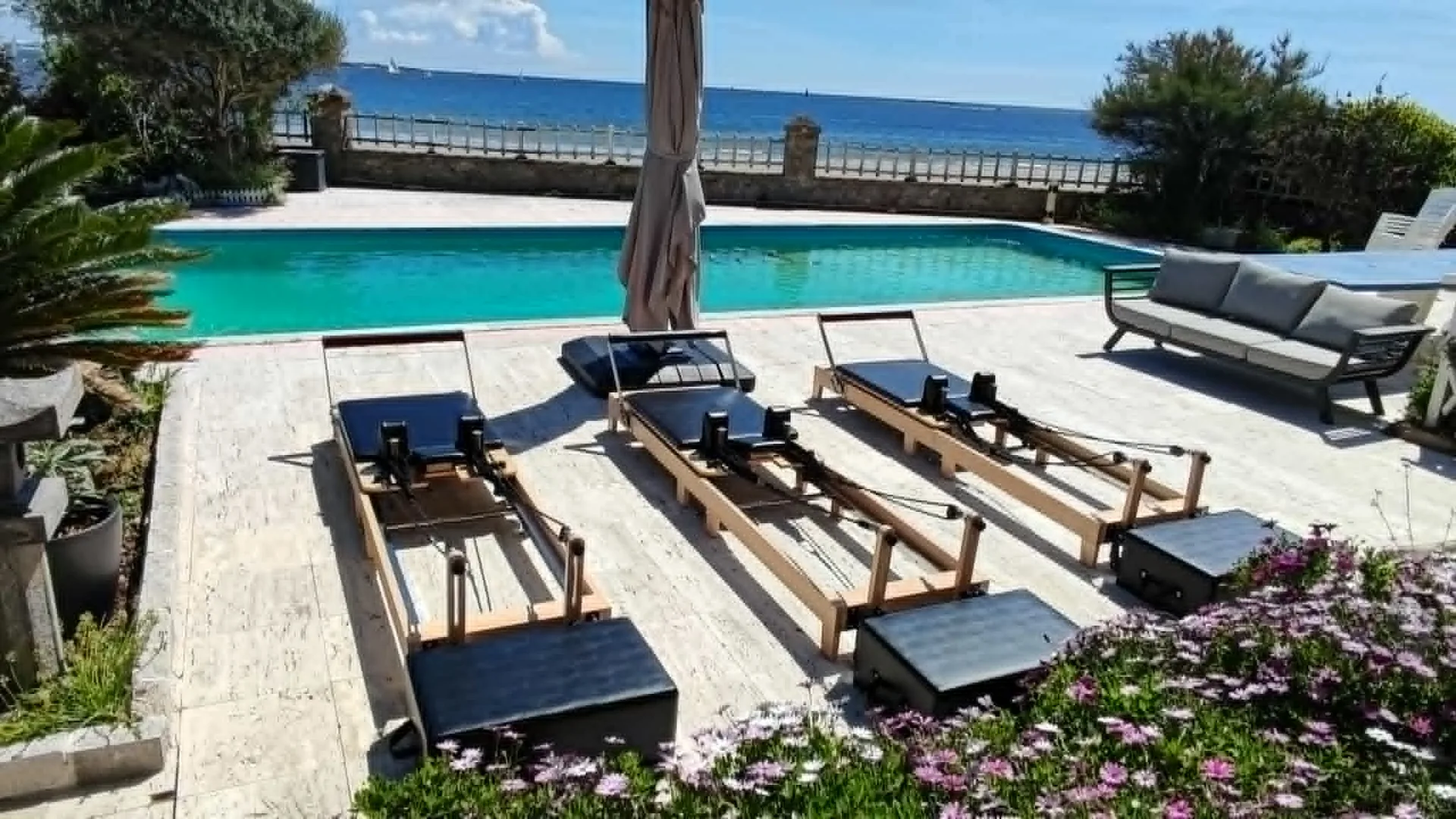 Trois Reformers Pilates installés au bord d'une piscine face à la mer à Larmor-Plage