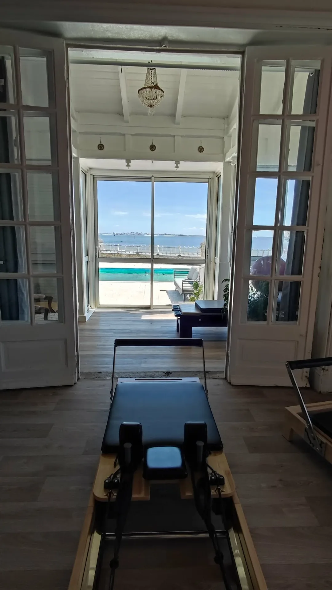 Reformer de Pilates face aux portes-fenêtres ouvertes sur la mer